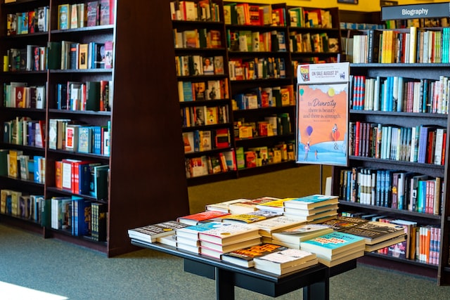 mesa y estantes llenos de libros en una exitosa libreria administrada con el mejor software punto de venta